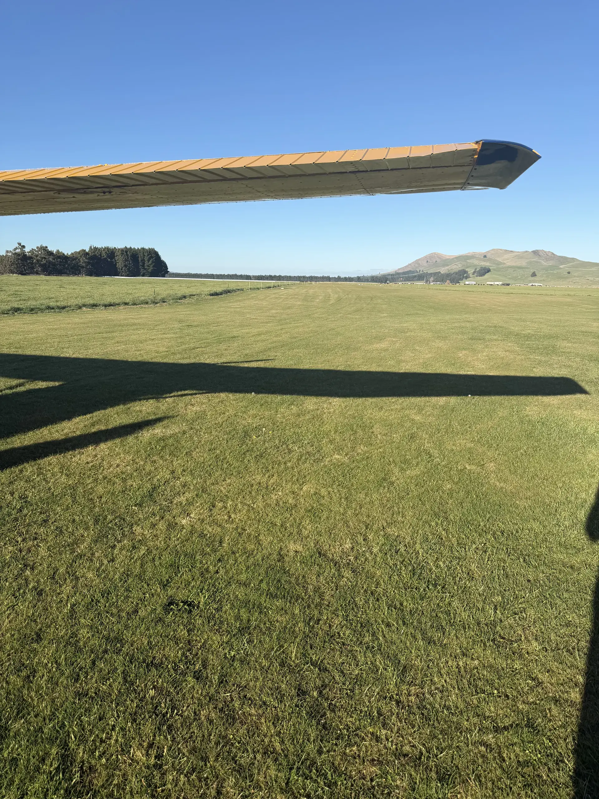 Flyinn aircraft wing over a grass airstrip